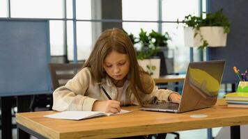 Pupil girl doing her homework using laptop in primary school. Child using technology on elementary computer science class video