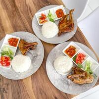 Ayam Goreng Lalapan. consisting of rice, fried chicken, tofu, tempeh, vegetables, and sambal photo