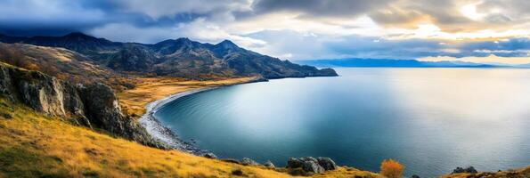 A serene ocean meets the rugged mountains on a crisp autumn day. The once vibrant vegetation is now a muted palette of browns. photo