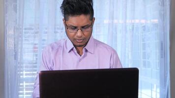 A man in glasses is using a laptop computer video