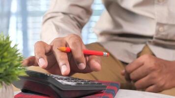 A man is using a calculator to calculate the cost of a car video