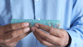 A man holding a pill box with pills in it video