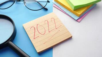 2020 calendar with magnifying glass and notepad on blue background video