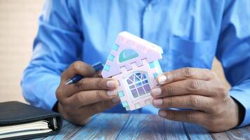 A man holding a toy house model on a table video