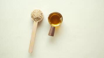 A spoon with honey and a spoon with sesame oil on a white background video