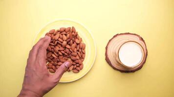 Hand holding a plate of almonds and a bowl of milk video