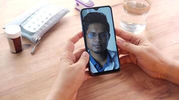 A man is using a smartphone to take a call with a doctor video