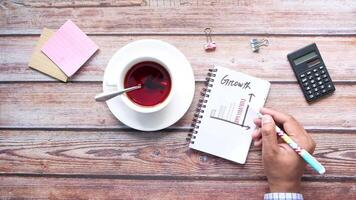 Businessman's hand writing on a notebook with a cup of coffee and calculator video
