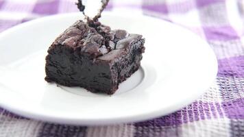 A piece of chocolate brownie is being dipped into a bowl video