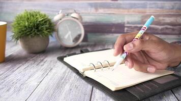 Hand writing in a notebook with a pen on a wooden table video
