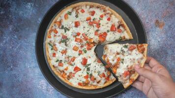 A hand holding a pizza with cheese and vegetables video