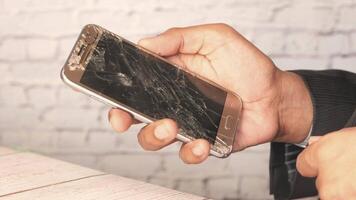 A person holding a broken cell phone with a broken screen video