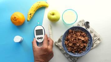 A person is holding a glucose meter next to a bowl of fruit and a bowl of cereal video