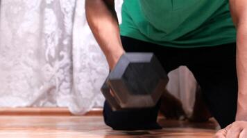 A man is squatting on the floor with a dumbbell video