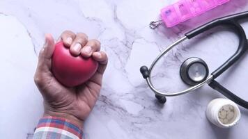 A person holding a red heart with a stethoscope next to it video