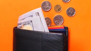Wallet with money and coins on orange background video