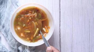 A bowl of vegetable soup with a spoon in it video