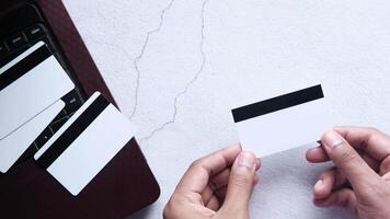 A person holding a credit card next to a laptop video