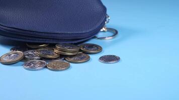 A blue purse with coins on a blue background video