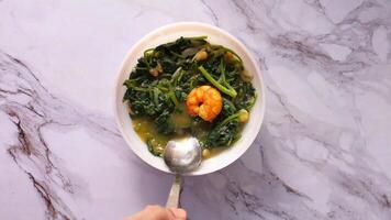 A bowl of soup with shrimp and spinach video