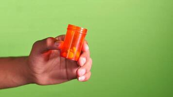A person holding an orange pill bottle on a green background video