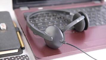 A pair of headphones is placed on a laptop video