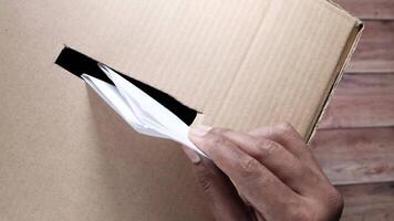 A person is holding a piece of paper out of a cardboard box video