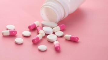 Pink pills spilling out of a bottle on a pink background video
