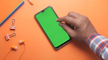 Man using smartphone with green screen on orange background video