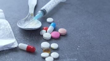 A spoon and a syringe with pills on a table video