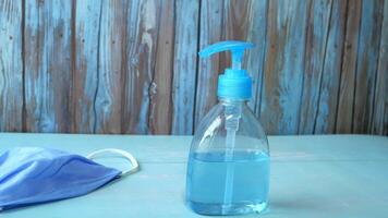 Hand sanitizer bottle and face mask on wooden background video