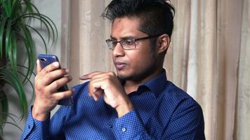 A man in glasses is looking at his phone video