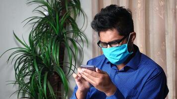 A man wearing a face mask while using his cell phone video