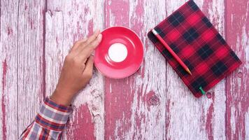 A person holding a red cup and a red notebook video