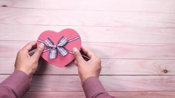 A person holding a heart shaped box with a bow on it video