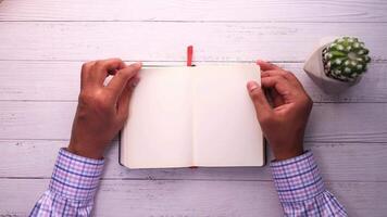 Man's hands writing in notebook on wooden table video