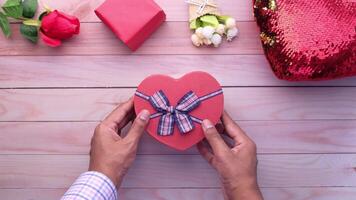 A person holding a heart shaped box with a bow on top video