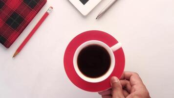 A person's hand holding a cup of coffee and a tablet computer on a white table video