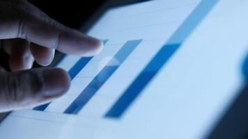 A person is pointing at a graph on a tablet video