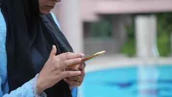A woman in a hijab is using her cell phone video