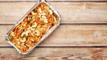 A container of food with nuts and vegetables on a wooden table video