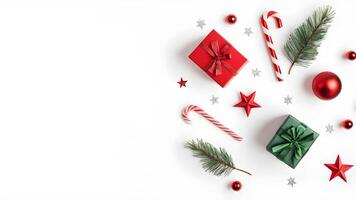 Top view layout with left blank space adorned red and green gift box, shiny balls, star, pine tree branch, candy cane on white background like snow photo