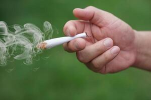 Close up hand holds homemade cigarette for smoking. Concept, smoking is bad for health. Private favorite for relaxation but can cause health problems respiratory disease and addict. photo