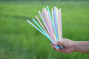Close up hand holds colorful plastic drinking straws tubes. Concept single use equipment for drinking, but can use for diy crafts for decoration. Reduce and recycle plastic tubes for environment. photo