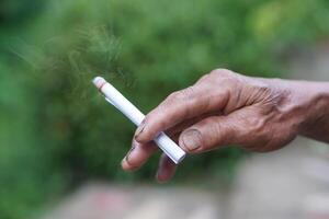 Close up hand holds homemade cigarette for smoking. Concept, smoking is bad for health. Private favorite for relaxation but can cause health problems respiratory disease and addict. photo