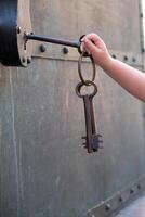a small child's hand tries to open a padlock with a large key photo