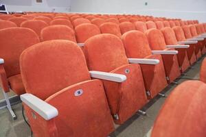 Side view of empty cinema hall with orange seats with copy space. Seats with numbers in theatre photo