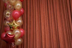 Orange closed curtain or drapery in theater with multicolored balloons with copy space. Theatrical performance concept. photo
