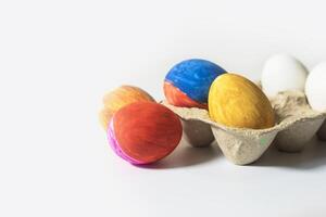 Colorful Easter eggs in egg carton isolated on white background. photo