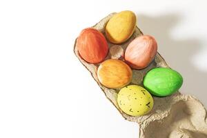 Colorful easter eggs in a cardboard box on a white background with copy space. photo